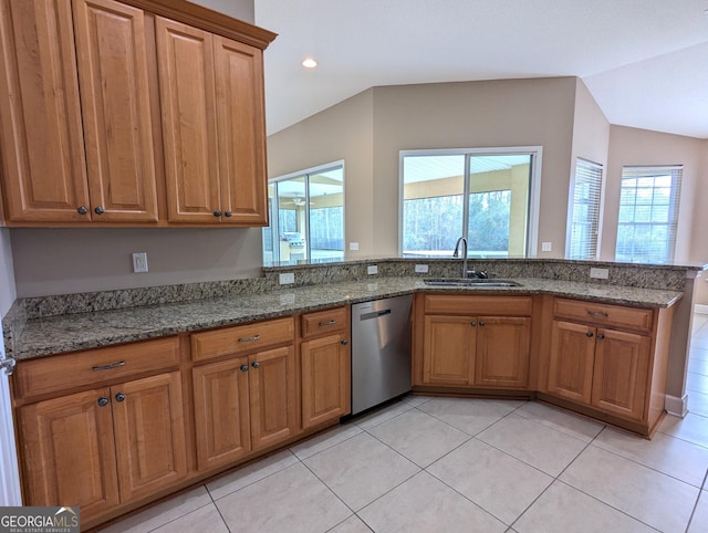 kitchen featuring dark stone counters, brown cabinets, dishwasher, and a sink