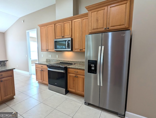 kitchen featuring light tile patterned floors, stone countertops, vaulted ceiling, appliances with stainless steel finishes, and brown cabinetry