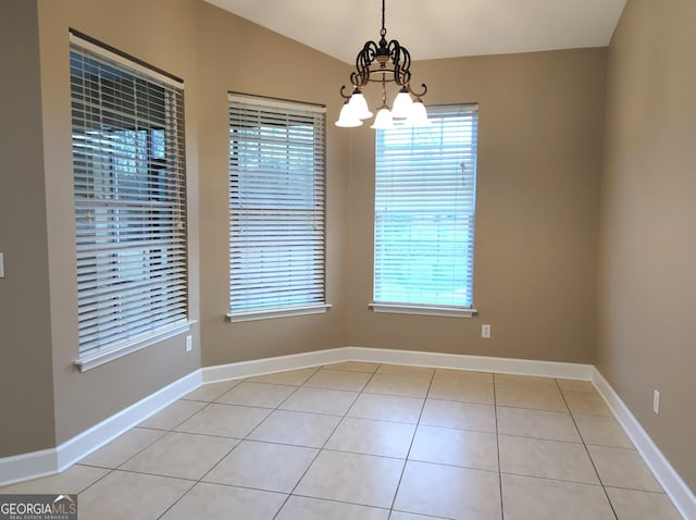 unfurnished dining area with lofted ceiling, light tile patterned flooring, baseboards, and a notable chandelier