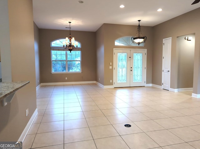 foyer entrance featuring light tile patterned floors, baseboards, and a notable chandelier