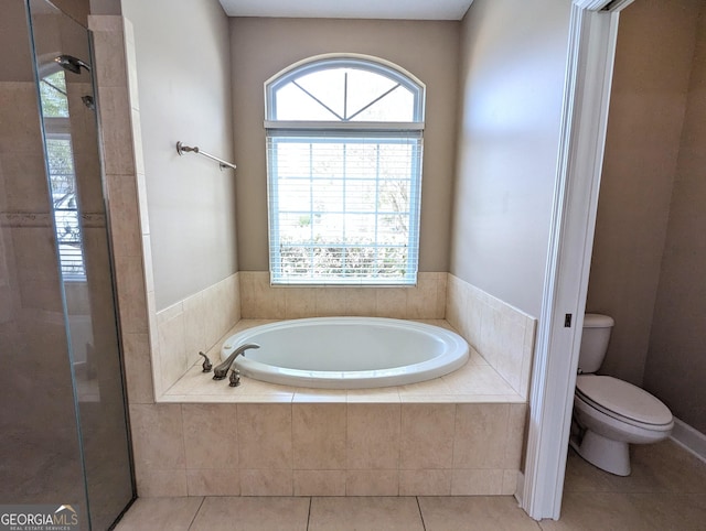 bathroom with a wealth of natural light, a garden tub, toilet, and tile patterned floors