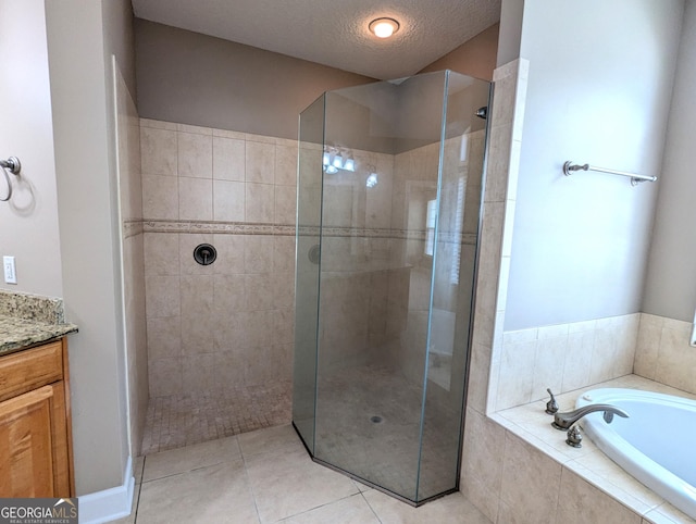 bathroom featuring a textured ceiling, vanity, a tile shower, a bath, and tile patterned floors