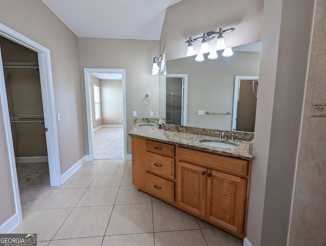 full bathroom with tile patterned flooring, a sink, baseboards, a spacious closet, and double vanity