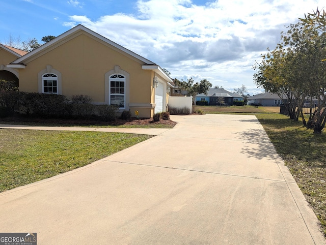 view of home's exterior featuring driveway, a garage, a lawn, and stucco siding