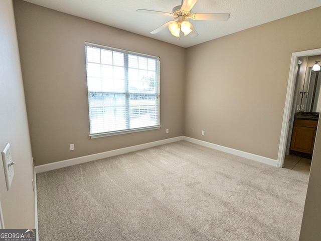 unfurnished room featuring light carpet, a ceiling fan, and baseboards