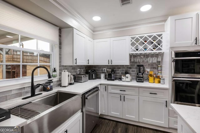 kitchen featuring appliances with stainless steel finishes, white cabinetry, light countertops, and a sink