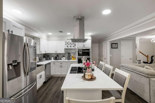 kitchen with island exhaust hood, stainless steel appliances, white cabinets, light stone countertops, and a kitchen bar