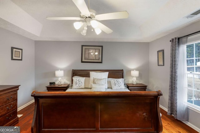 bedroom with visible vents, a raised ceiling, and wood finished floors