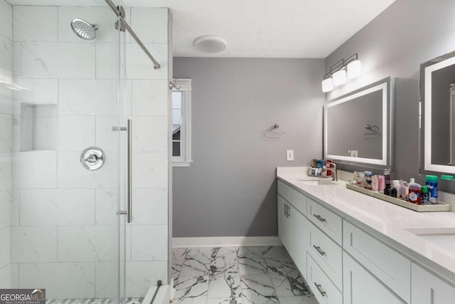 full bathroom featuring double vanity, baseboards, marble finish floor, a shower stall, and a sink