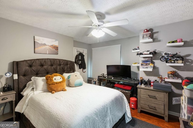 bedroom with a ceiling fan, dark wood-style flooring, and a textured ceiling