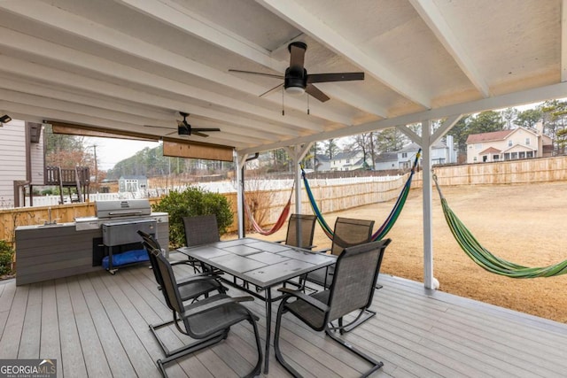 wooden deck with outdoor dining area, a playground, a fenced backyard, and a ceiling fan