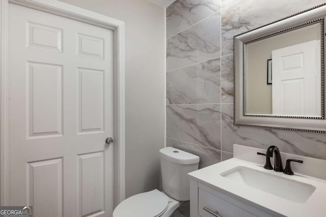 half bath featuring tasteful backsplash, tile walls, vanity, and toilet