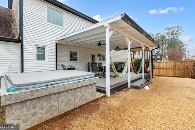 back of house featuring ceiling fan, fence, a covered hot tub, roof with shingles, and a wooden deck