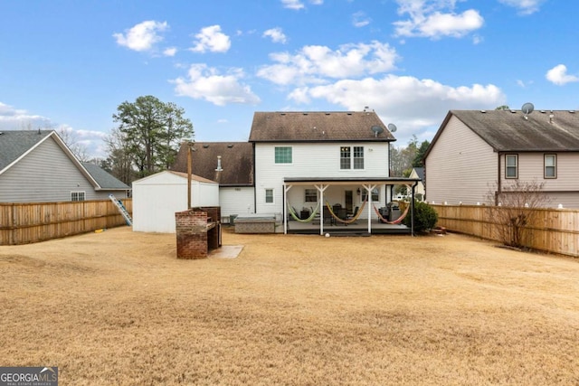 rear view of property with a storage shed, a fenced backyard, a patio area, and an outbuilding