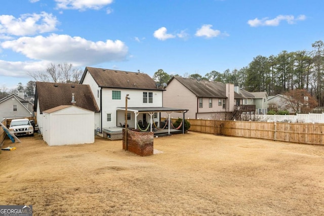 rear view of property with a residential view, fence, an outbuilding, and a storage unit