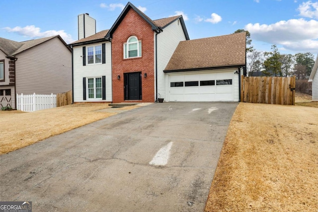 view of front of house with driveway, a chimney, an attached garage, fence, and a front lawn