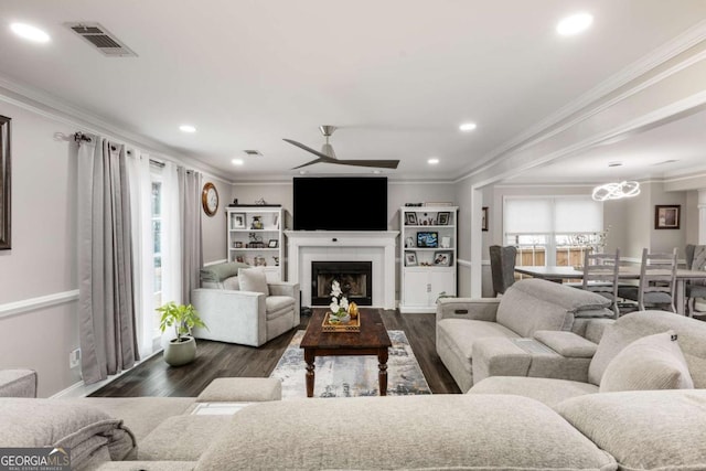 living area featuring recessed lighting, visible vents, dark wood-type flooring, and ornamental molding