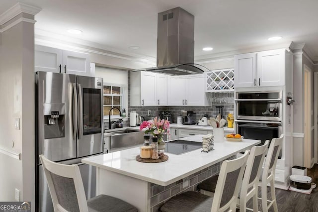 kitchen featuring white cabinets, appliances with stainless steel finishes, a breakfast bar area, island exhaust hood, and light countertops