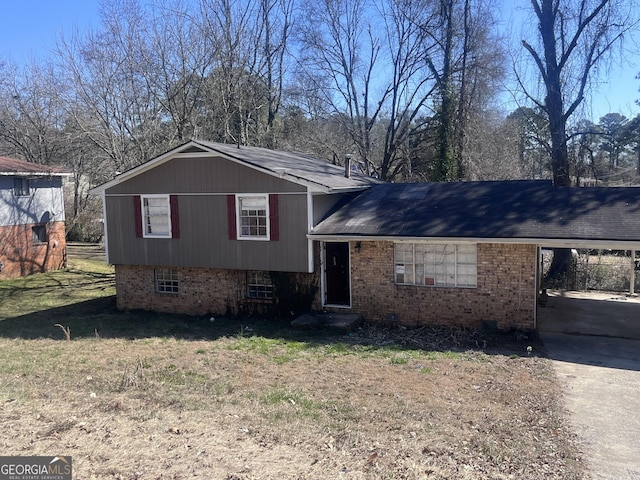 split level home featuring a front yard, an attached carport, concrete driveway, and brick siding