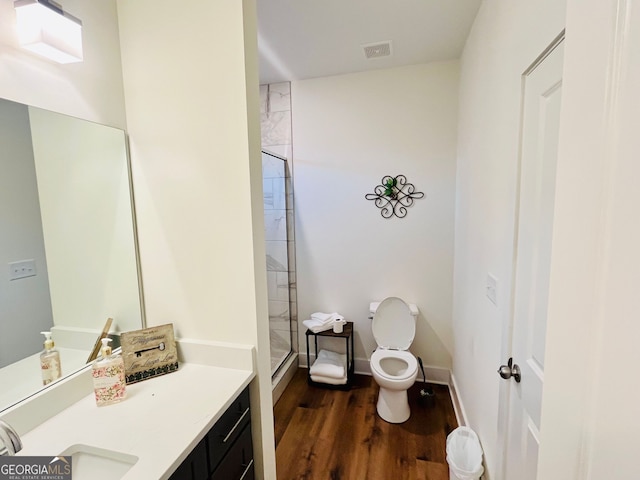 full bathroom featuring a stall shower, baseboards, toilet, wood finished floors, and vanity