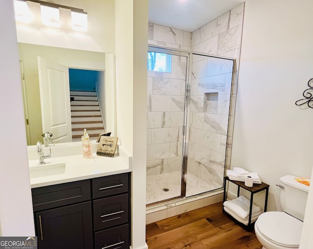 full bath with vanity, a stall shower, wood finished floors, and toilet