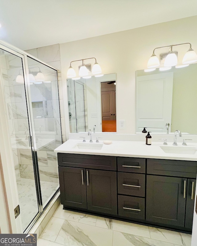 bathroom with double vanity, marble finish floor, a shower stall, and a sink