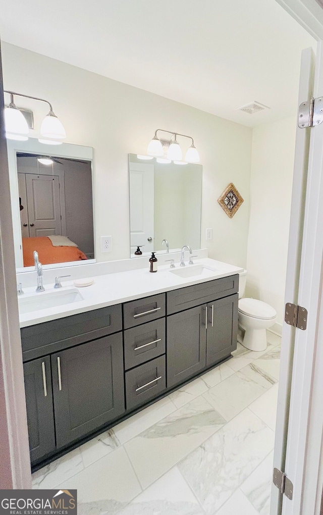 bathroom with double vanity, marble finish floor, toilet, and a sink