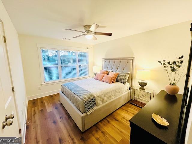 bedroom featuring a ceiling fan, wood finished floors, visible vents, and baseboards