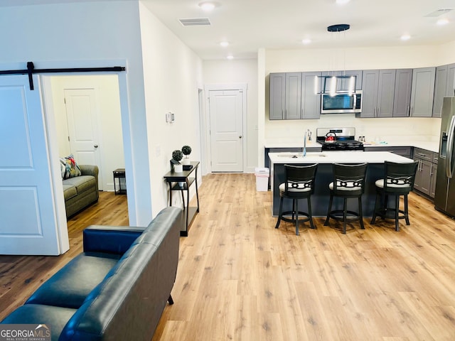 kitchen with a breakfast bar, visible vents, light countertops, appliances with stainless steel finishes, and a center island with sink