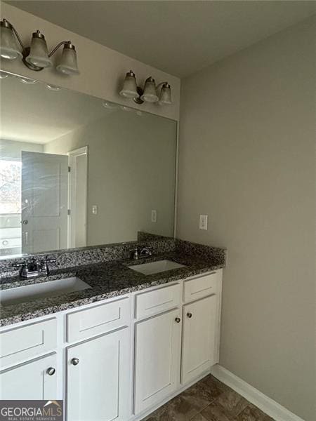 bathroom featuring double vanity, baseboards, and a sink