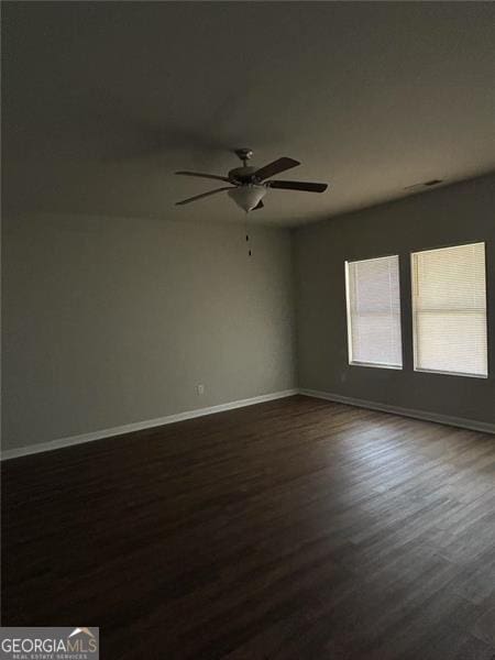 spare room featuring dark wood-style floors, ceiling fan, and baseboards