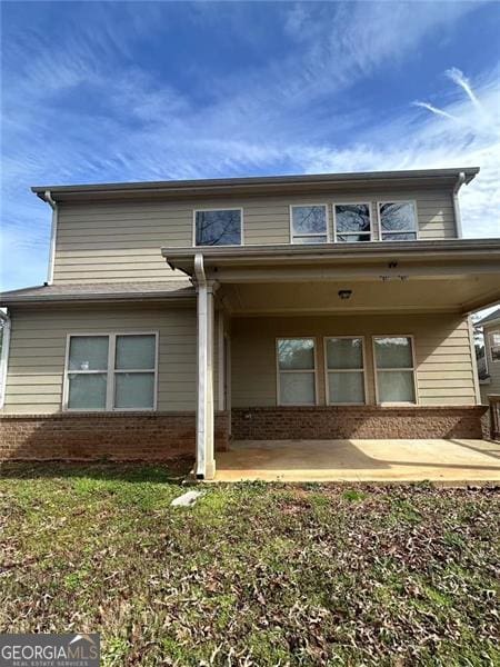 view of front of house featuring brick siding and a patio area