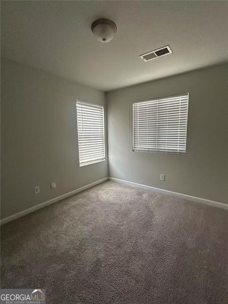 unfurnished room featuring carpet floors, visible vents, and baseboards