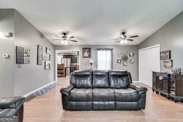 living room with vaulted ceiling, baseboards, and light wood-style floors