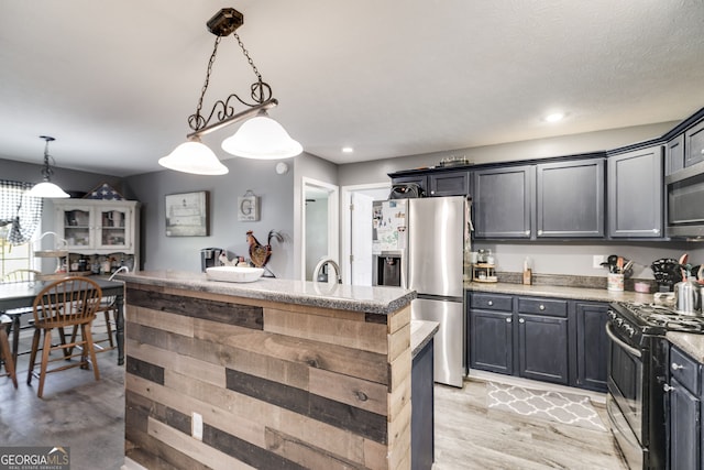 kitchen featuring dark cabinets, stainless steel appliances, a center island, hanging light fixtures, and light stone countertops