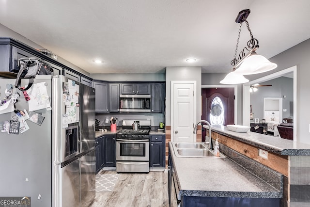 kitchen featuring ceiling fan, light wood-style flooring, a sink, appliances with stainless steel finishes, and decorative light fixtures