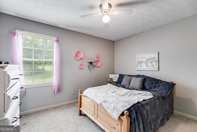 bedroom with light colored carpet, ceiling fan, a textured ceiling, and baseboards