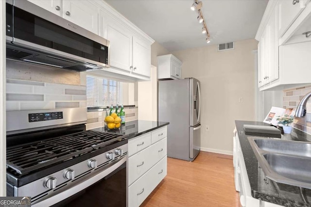 kitchen with light wood finished floors, tasteful backsplash, visible vents, appliances with stainless steel finishes, and white cabinetry