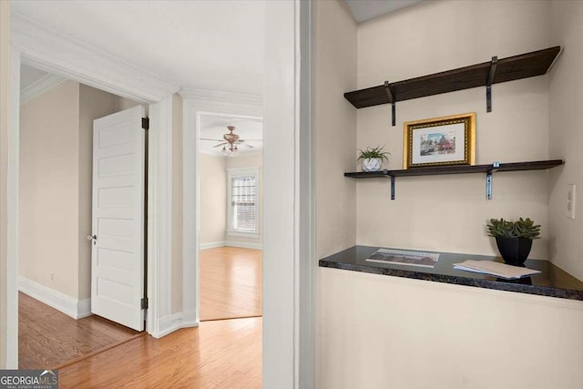 bar with ornamental molding, wood finished floors, a ceiling fan, and baseboards