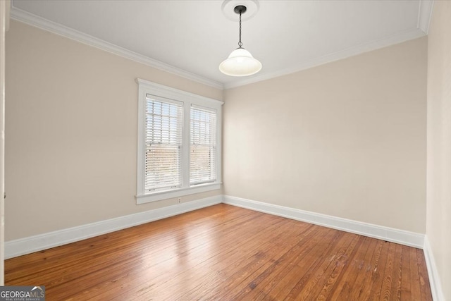 spare room featuring baseboards, ornamental molding, and wood finished floors