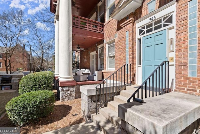 doorway to property featuring brick siding and a ceiling fan