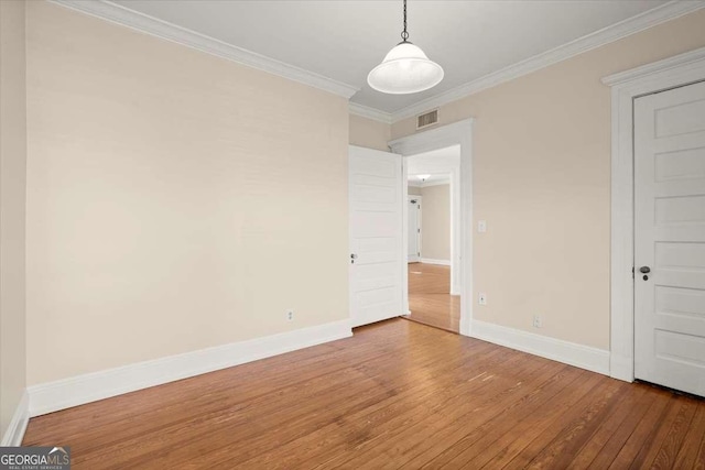 unfurnished room featuring ornamental molding, visible vents, baseboards, and wood finished floors