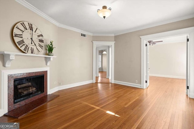 unfurnished living room with visible vents, a fireplace with raised hearth, light wood-style flooring, ornamental molding, and baseboards