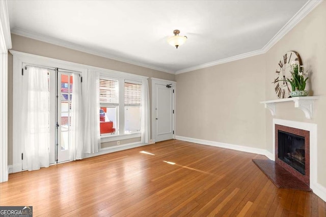 unfurnished living room with crown molding, baseboards, a fireplace with raised hearth, and wood finished floors