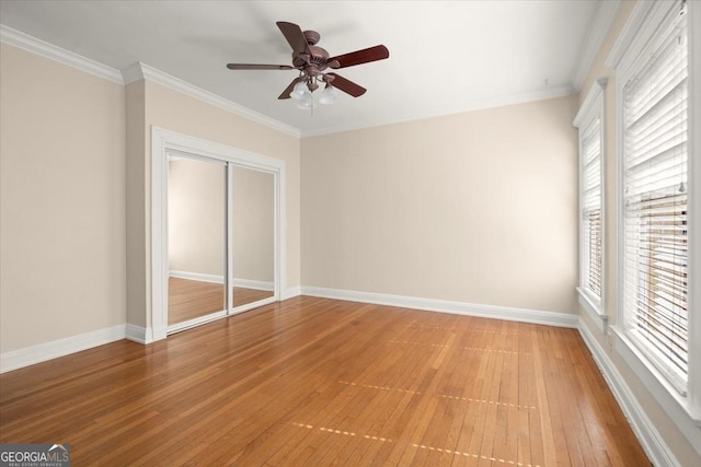 unfurnished bedroom featuring crown molding, a closet, baseboards, and wood finished floors