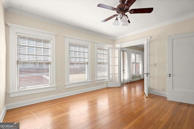 spare room featuring light wood finished floors, a ceiling fan, baseboards, and crown molding