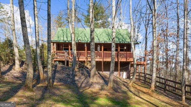 back of property with metal roof, dirt driveway, and a deck