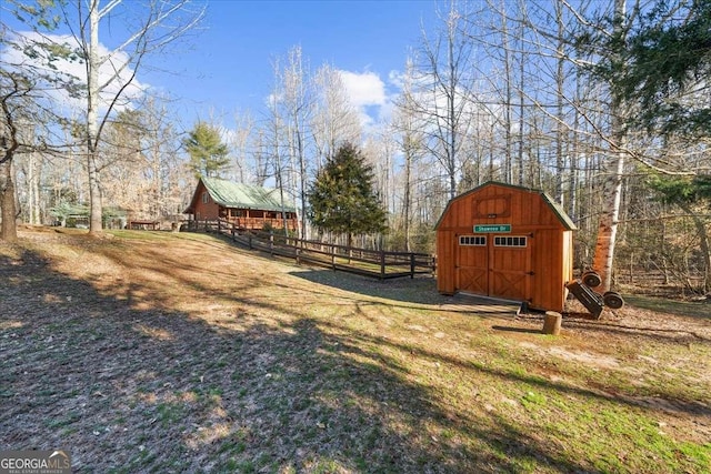 view of yard with an outdoor structure, fence, and a shed