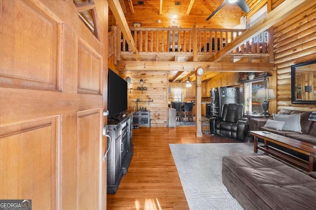 living area with rustic walls, wooden ceiling, a towering ceiling, and wood finished floors