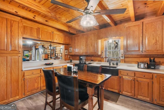 kitchen featuring a sink, wood ceiling, light countertops, brown cabinets, and light wood finished floors